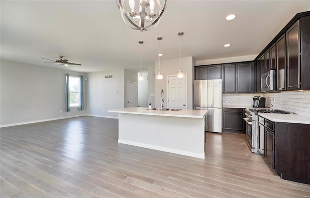 kitchen with ceiling fan with notable chandelier, decorative light fixtures, appliances with stainless steel finishes, light hardwood / wood-style floors, and sink