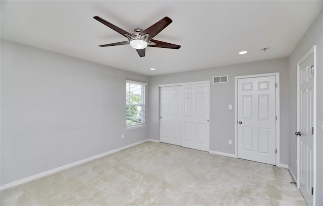 unfurnished bedroom featuring two closets, ceiling fan, and light colored carpet