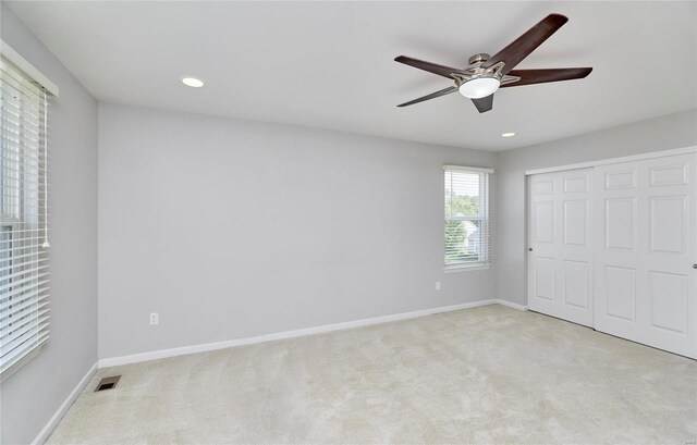 unfurnished bedroom featuring a closet, ceiling fan, and light carpet