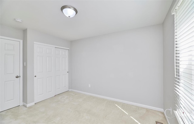 unfurnished bedroom with light carpet, multiple windows, and a closet