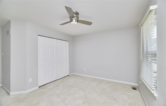 unfurnished bedroom with light colored carpet, ceiling fan, and a closet