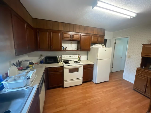 kitchen with light hardwood / wood-style floors, a textured ceiling, and white appliances