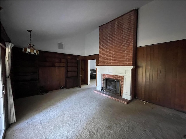 unfurnished living room with carpet flooring, a fireplace, wooden walls, and a high ceiling