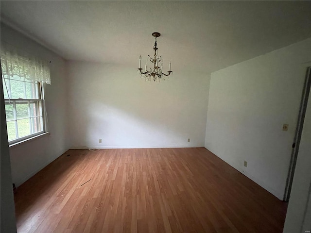 unfurnished room featuring wood-type flooring and a notable chandelier