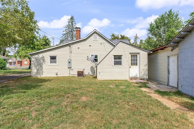 rear view of property featuring a chimney, a yard, and central air condition unit