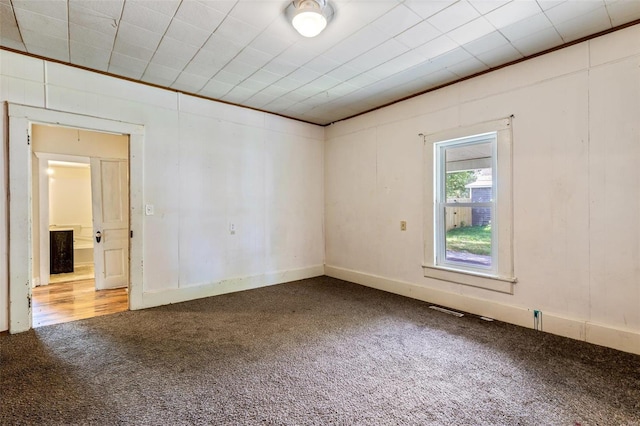 carpeted empty room featuring crown molding and visible vents