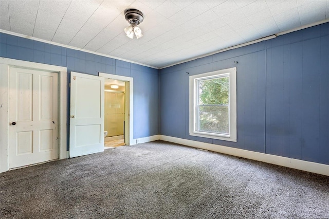 unfurnished bedroom with carpet flooring, ensuite bath, and ornamental molding