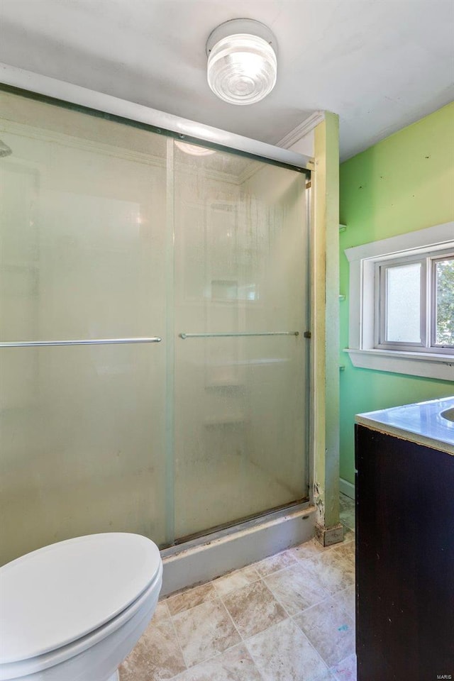 bathroom featuring vanity, toilet, and a shower with shower door