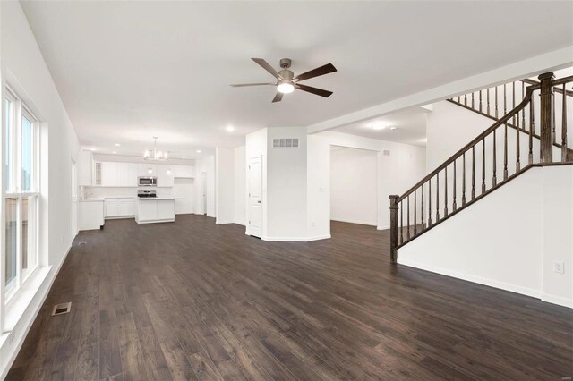 unfurnished living room featuring dark hardwood / wood-style floors and ceiling fan with notable chandelier