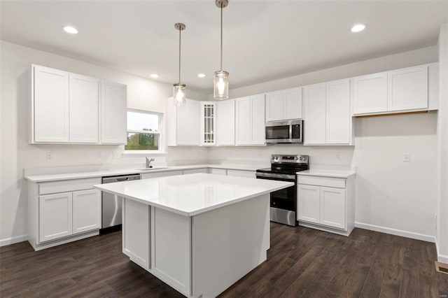 kitchen featuring hanging light fixtures, dark hardwood / wood-style flooring, appliances with stainless steel finishes, and white cabinets