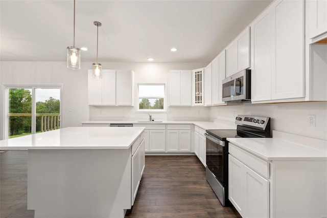 kitchen featuring dark wood-type flooring, stainless steel appliances, sink, a center island, and white cabinetry