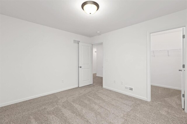 unfurnished bedroom with a closet, a spacious closet, and light colored carpet