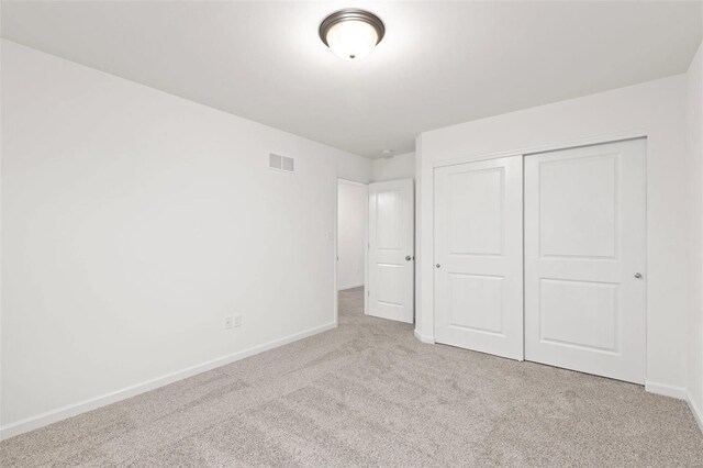 unfurnished bedroom with light carpet and a closet