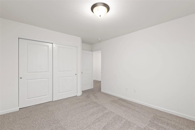 unfurnished bedroom with light carpet and a closet