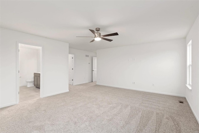 interior space featuring ceiling fan, light colored carpet, and ensuite bath