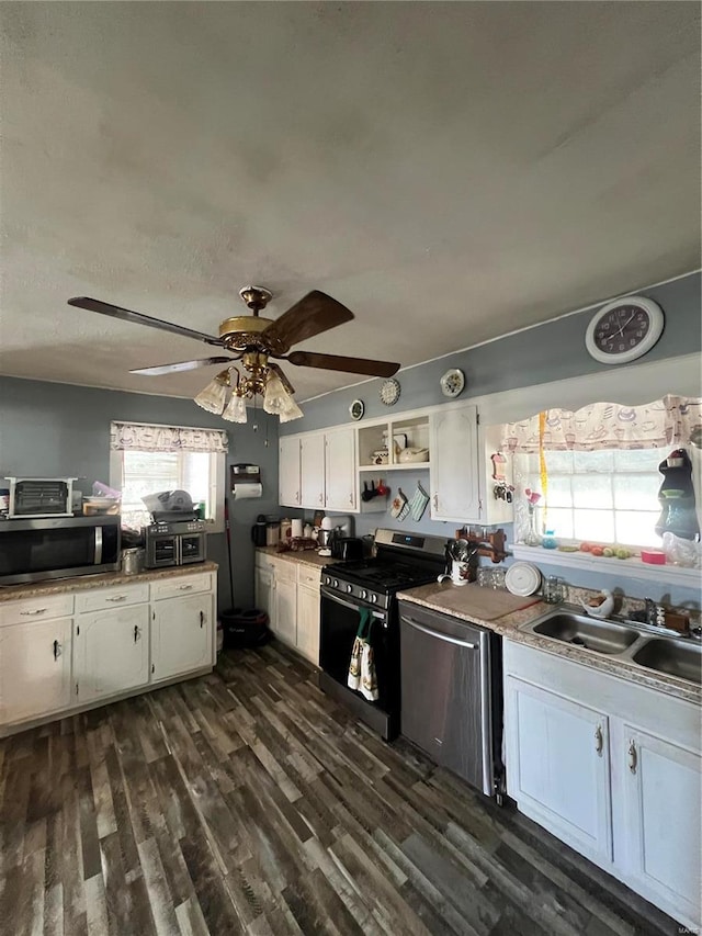 kitchen with white cabinetry, stainless steel appliances, sink, ceiling fan, and dark wood-type flooring