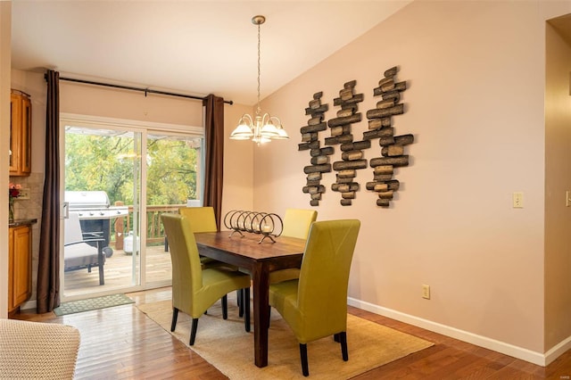 dining room with light wood-type flooring, a notable chandelier, and vaulted ceiling