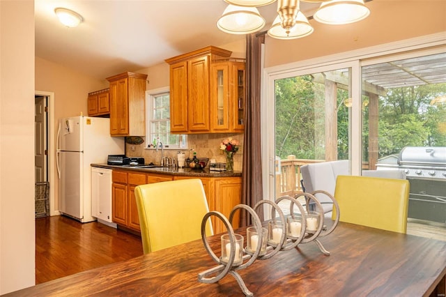 kitchen with vaulted ceiling, dark hardwood / wood-style flooring, a wealth of natural light, and white appliances