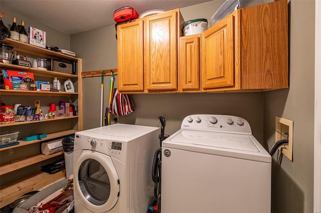 washroom with a textured ceiling, cabinets, and washing machine and dryer