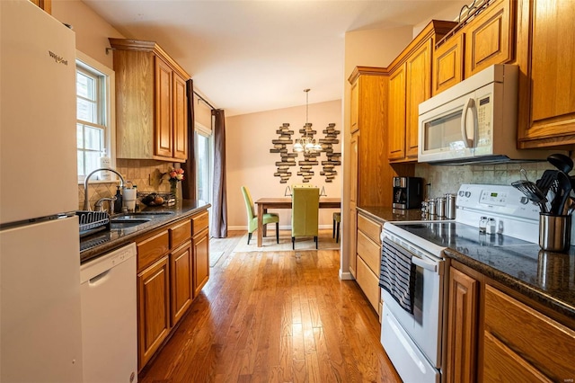 kitchen featuring hanging light fixtures, hardwood / wood-style flooring, vaulted ceiling, white appliances, and decorative backsplash