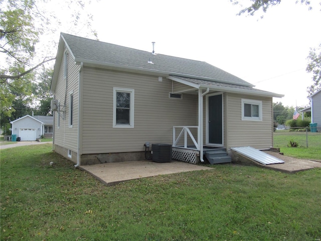 rear view of house with a shingled roof, fence, cooling unit, a yard, and a patio area