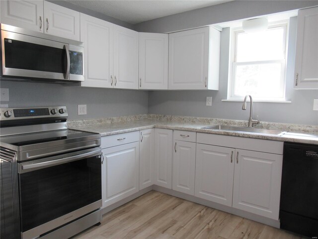 kitchen with white cabinets, stainless steel appliances, light hardwood / wood-style floors, and sink