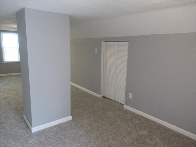 carpeted spare room featuring lofted ceiling