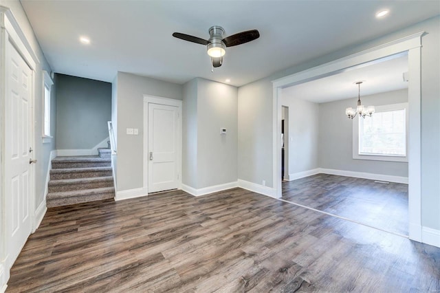 spare room featuring dark wood-type flooring and ceiling fan with notable chandelier