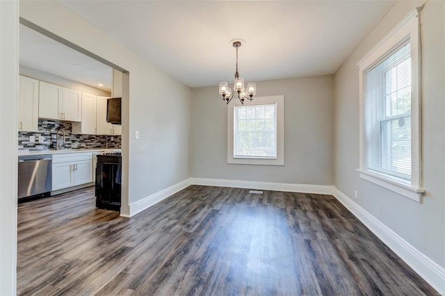 kitchen with an inviting chandelier, decorative light fixtures, stainless steel dishwasher, dark wood-type flooring, and white cabinetry