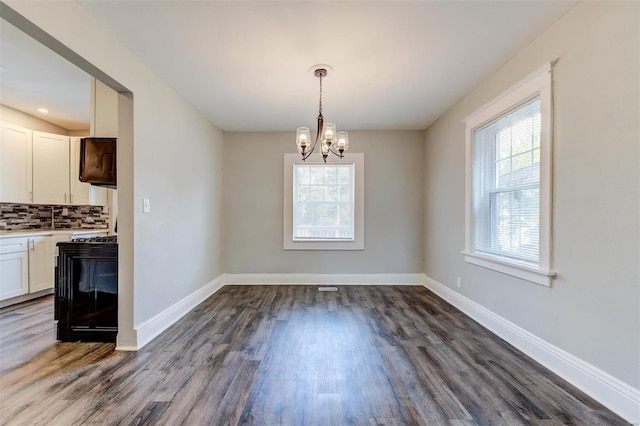 unfurnished dining area with dark wood-type flooring and an inviting chandelier