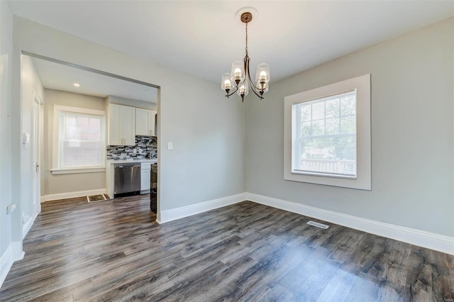 unfurnished dining area with dark hardwood / wood-style flooring and a chandelier