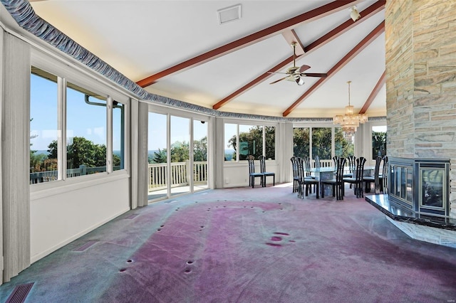 sunroom / solarium with lofted ceiling with beams, a stone fireplace, and ceiling fan with notable chandelier