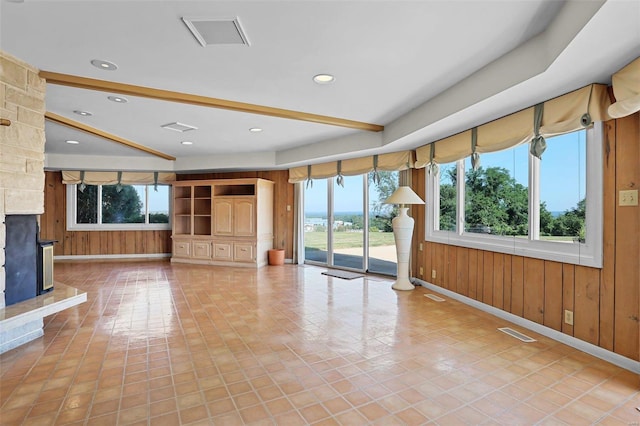 unfurnished living room with light tile patterned flooring, a stone fireplace, and wood walls