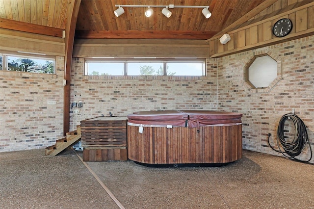 misc room featuring vaulted ceiling with beams, wooden ceiling, a healthy amount of sunlight, and brick wall