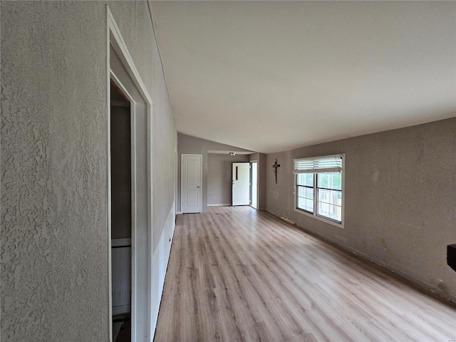 empty room featuring light wood-type flooring and vaulted ceiling