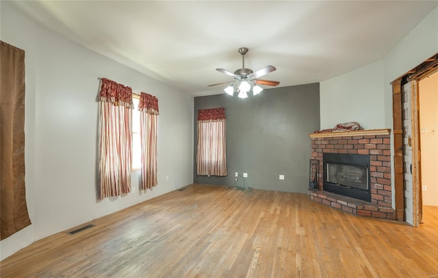 unfurnished living room with light hardwood / wood-style flooring, ceiling fan, and a brick fireplace