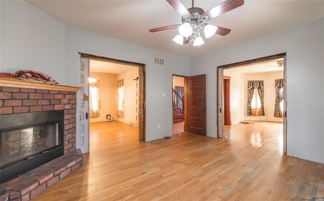 living room featuring a brick fireplace, ceiling fan, and light wood-type flooring