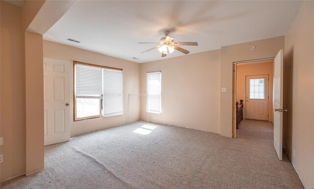 spare room featuring ceiling fan, light colored carpet, and plenty of natural light