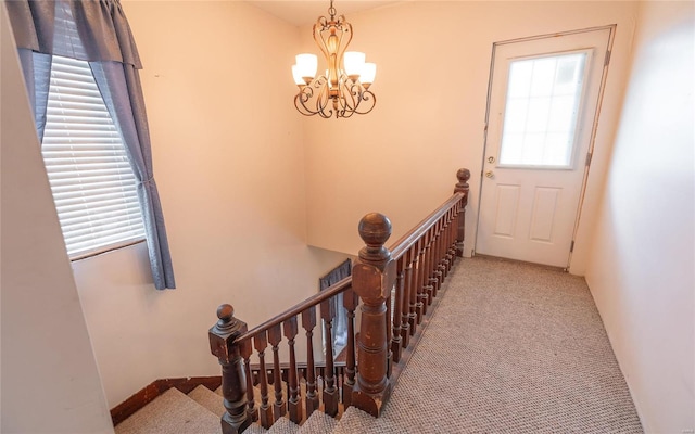 staircase with carpet flooring and a chandelier