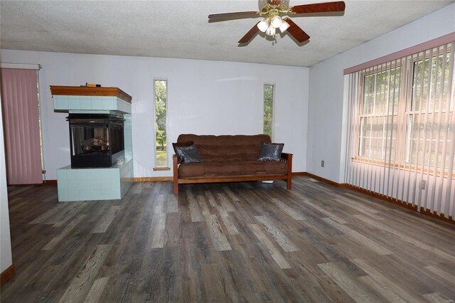 living room featuring a tile fireplace, dark hardwood / wood-style flooring, ceiling fan, and plenty of natural light