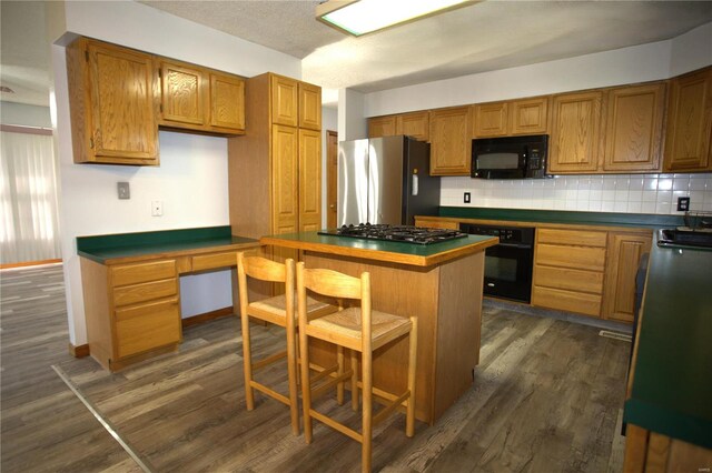 kitchen with a kitchen breakfast bar, dark wood-type flooring, backsplash, a kitchen island, and black appliances