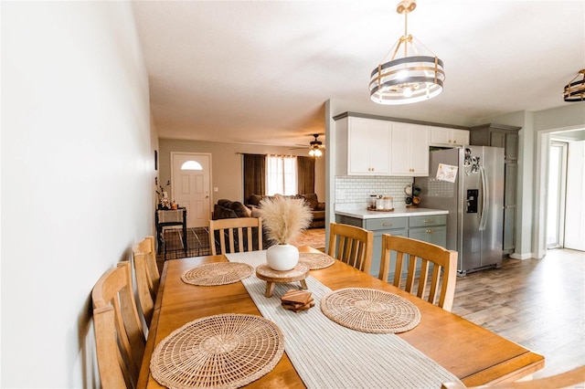 dining area featuring light hardwood / wood-style flooring and ceiling fan with notable chandelier