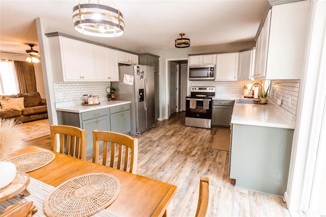 kitchen featuring appliances with stainless steel finishes, gray cabinetry, backsplash, light hardwood / wood-style flooring, and sink