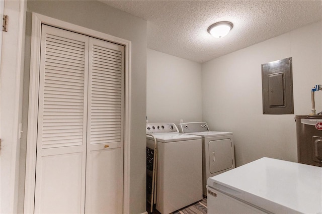 laundry room featuring separate washer and dryer, electric panel, light wood-type flooring, and a textured ceiling