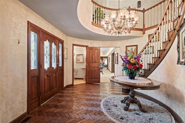 entryway with a notable chandelier, a towering ceiling, and dark parquet floors