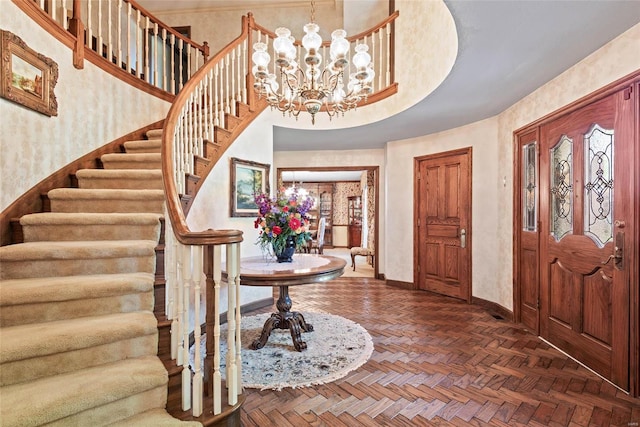 foyer entrance with an inviting chandelier and dark parquet flooring