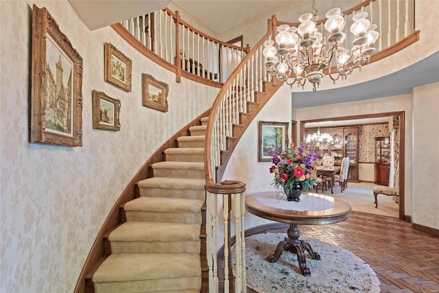 staircase featuring a chandelier, parquet floors, and a high ceiling