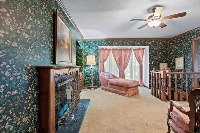 sitting room featuring a textured ceiling, carpet flooring, ornamental molding, and ceiling fan