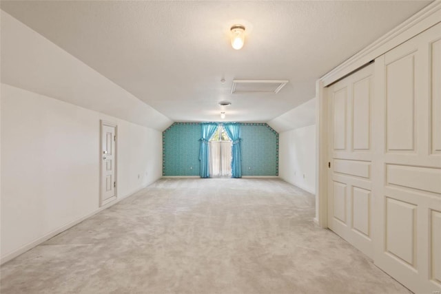 bonus room with a textured ceiling, vaulted ceiling, and light colored carpet