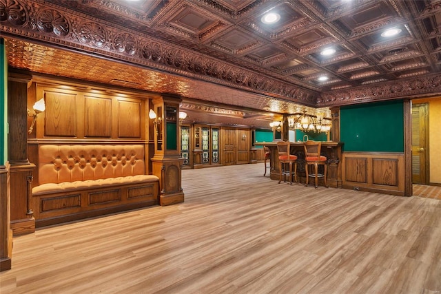 miscellaneous room with decorative columns, bar, crown molding, and light hardwood / wood-style flooring